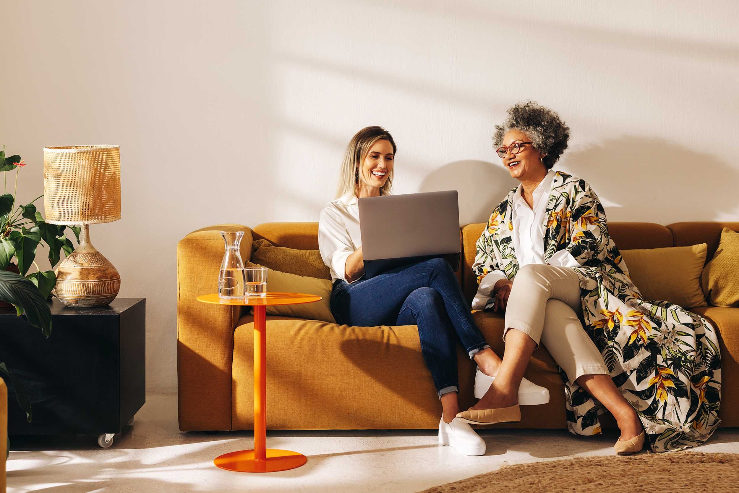 two woman looking at a computer in a couch